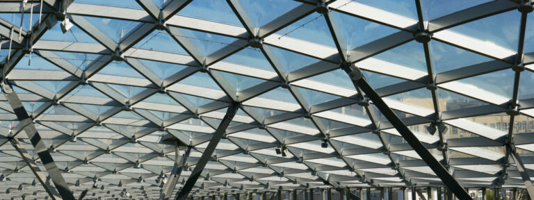The glass ceiling of the modern building supports a steel beams